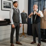 Two men in a fashion studio discussing suit designs, focusing on tailoring and style.